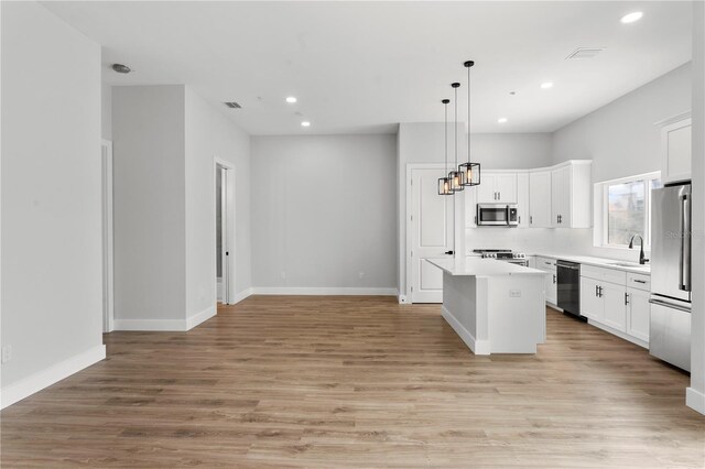 11605 1st St E Unit 2, Treasure Island, FL 33706 - kitchen featuring stainless steel appliances, open floor plan, a kitchen island, recessed lighting, and white cabinetry