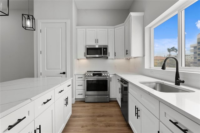 11605 1st St E Unit 2, Treasure Island, FL 33706 - kitchen with stainless steel appliances, backsplash, light stone countertops, white cabinetry, and dark wood-type flooring