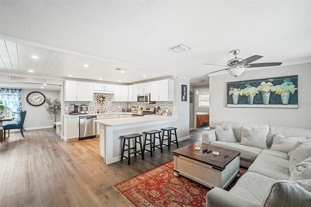 980 8th Ave NE, Largo, FL 33770 - living room with healthy amount of natural light, light wood finished floors, recessed lighting, a ceiling fan, and ornamental molding