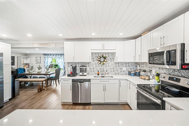 980 8th Ave NE, Largo, FL 33770 - kitchen with appliances with stainless steel finishes, white cabinetry, wood finished floors, decorative backsplash, and recessed lighting