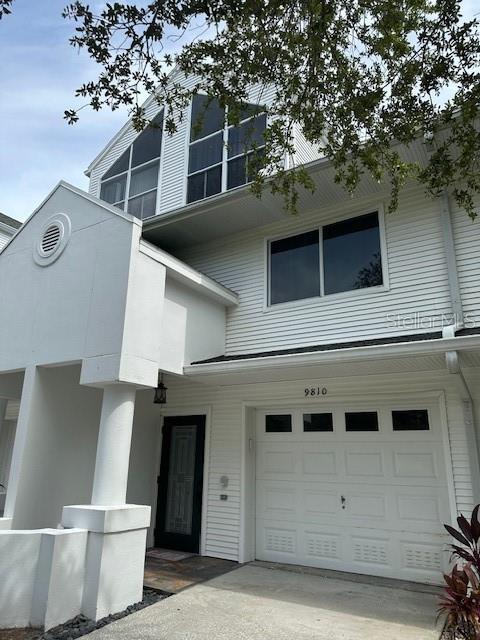 9810 Indian Key Trl Unit 85, Seminole, FL 33776 - view of front of house featuring a garage, concrete driveway, and stucco siding
