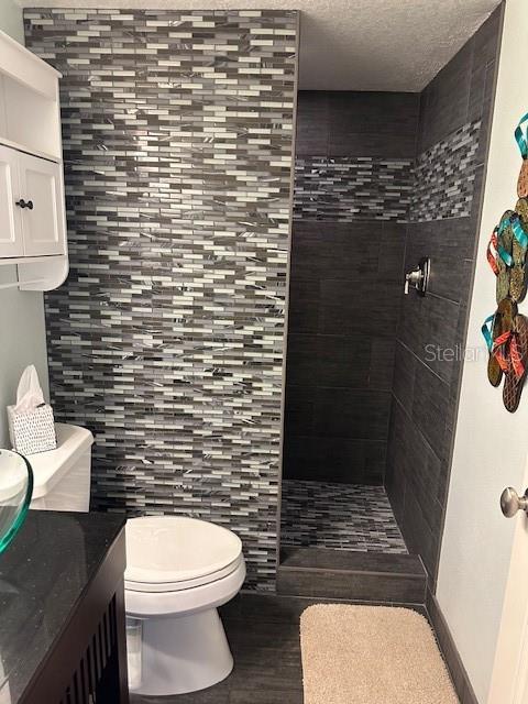 9810 Indian Key Trl Unit 85, Seminole, FL 33776 - full bath featuring a tile shower, vanity, a textured ceiling, and wood finished floors