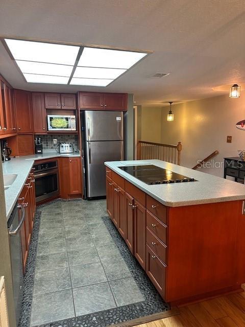 9810 Indian Key Trl Unit 85, Seminole, FL 33776 - kitchen with stainless steel appliances, backsplash, light countertops, and a center island