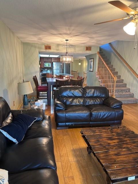 9810 Indian Key Trl Unit 85, Seminole, FL 33776 - living area featuring stairs, a ceiling fan, wood finished floors, and a chandelier