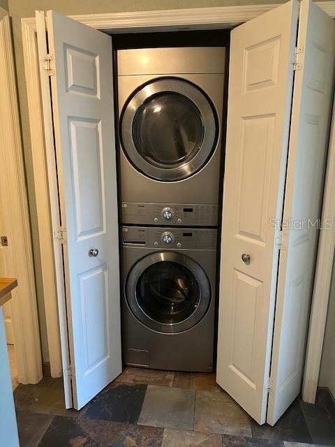 9810 Indian Key Trl Unit 85, Seminole, FL 33776 - laundry room with stacked washer and clothes dryer and dark stone finish floors