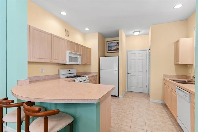 2468 Magnolia Cir, North Port, FL 34289 - kitchen with white appliances, a peninsula, a breakfast bar area, light brown cabinets, and light countertops
