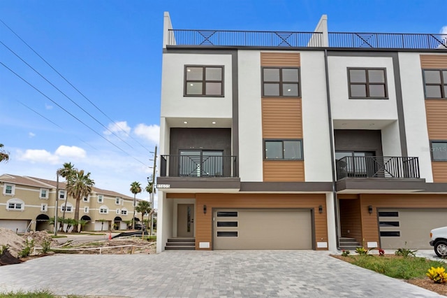 11605 1st St E Unit 3, Treasure Island, FL 33706 - view of front of house with stucco siding, a garage, a balcony, and decorative driveway