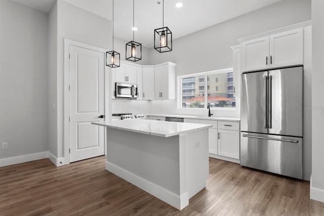11605 1st St E Unit 3, Treasure Island, FL 33706 - kitchen featuring appliances with stainless steel finishes, a center island, white cabinetry, wood finished floors, and recessed lighting