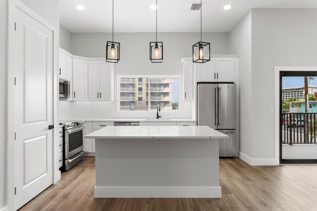 11605 1st St E Unit 3, Treasure Island, FL 33706 - kitchen featuring stainless steel appliances, light wood-style flooring, a kitchen island, light countertops, and recessed lighting