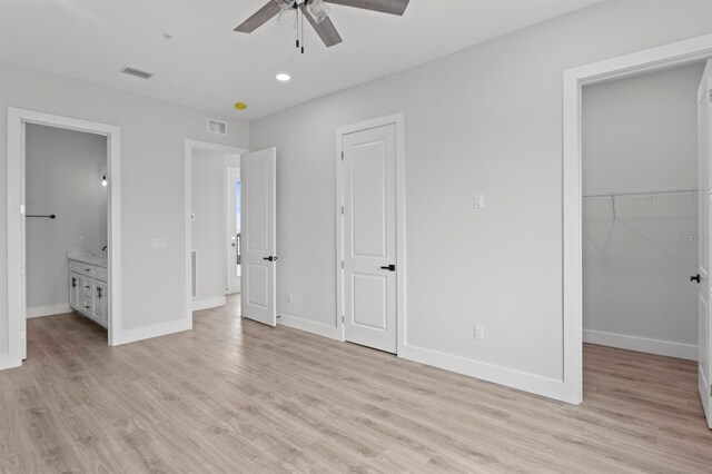 11605 1st St E Unit 3, Treasure Island, FL 33706 - unfurnished bedroom featuring light wood-style flooring, a walk in closet, ensuite bathroom, recessed lighting, and ceiling fan