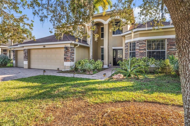 1872 Eloise Cove Dr, Winter Haven, FL 33884 - view of front facade featuring stone siding, stucco siding, a front yard, a garage, and decorative driveway