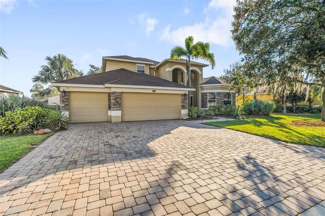 1872 Eloise Cove Dr, Winter Haven, FL 33884 - view of front of house featuring decorative driveway, a garage, a front yard, stone siding, and stucco siding