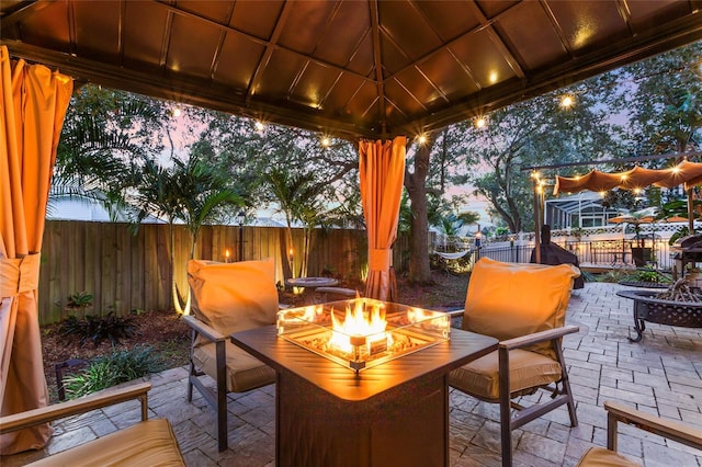 1872 Eloise Cove Dr, Winter Haven, FL 33884 - patio terrace at dusk with a fire pit, a patio area, a fenced backyard, and a gazebo