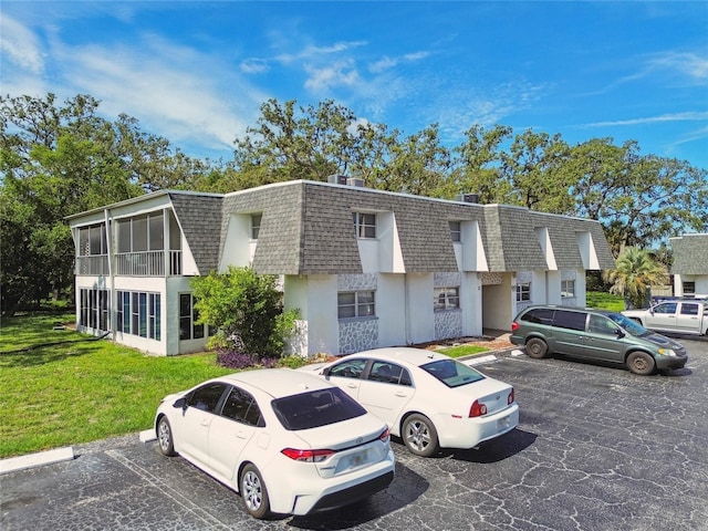 3415 Tricon Ln Unit 13, Holiday, FL 34691 - view of front facade with roof with shingles, mansard roof, uncovered parking, and stucco siding