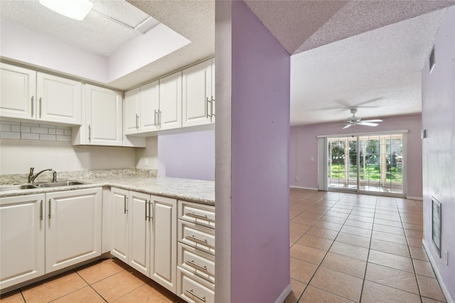 3415 Tricon Ln Unit 13, Holiday, FL 34691 - kitchen with a textured ceiling, light tile patterned floors, light countertops, white cabinetry, and a ceiling fan