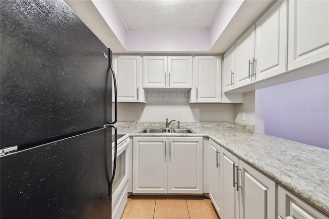 3415 Tricon Ln Unit 13, Holiday, FL 34691 - kitchen with freestanding refrigerator, light countertops, white cabinetry, light tile patterned floors, and a textured ceiling