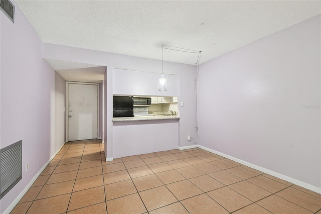 3415 Tricon Ln Unit 13, Holiday, FL 34691 - kitchen with stainless steel microwave, freestanding refrigerator, light countertops, white cabinetry, and pendant lighting