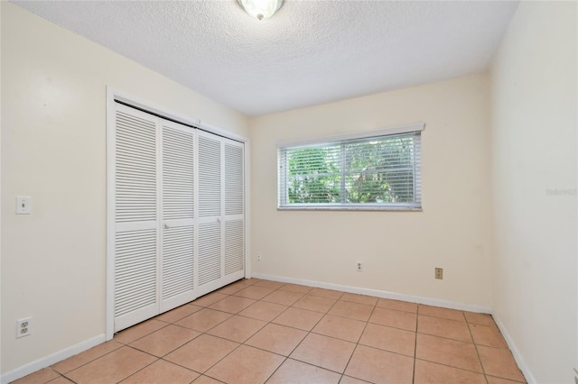 3415 Tricon Ln Unit 13, Holiday, FL 34691 - unfurnished bedroom featuring a closet, a textured ceiling, and light tile patterned floors