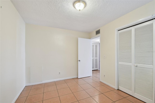 3415 Tricon Ln Unit 13, Holiday, FL 34691 - unfurnished bedroom featuring a textured ceiling, a closet, and light tile patterned flooring