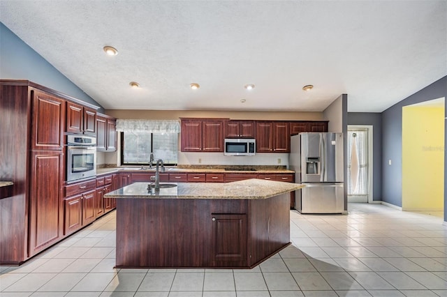 3685 N Palomino Ter, Beverly Hills, FL 34465 - kitchen featuring stainless steel appliances, vaulted ceiling, reddish brown cabinets, an island with sink, and light tile patterned floors