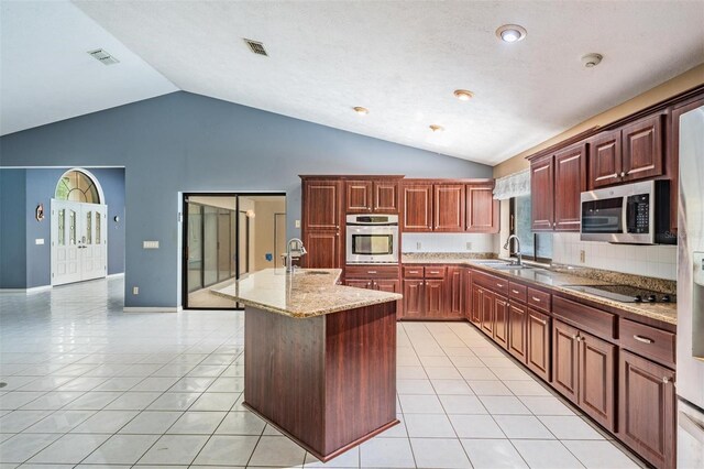 3685 N Palomino Ter, Beverly Hills, FL 34465 - kitchen featuring stainless steel appliances, an island with sink, light tile patterned floors, tasteful backsplash, and high vaulted ceiling
