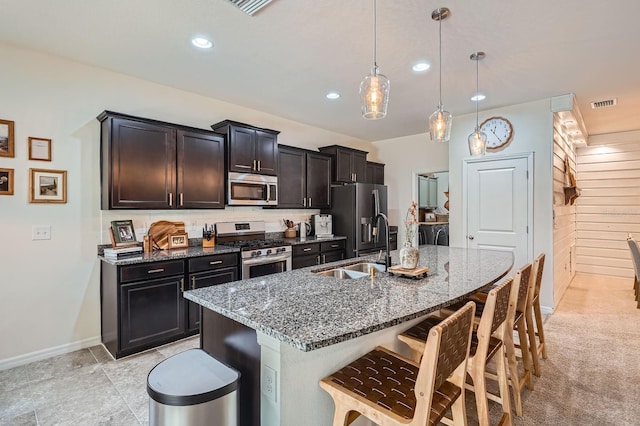 6307 Shadowlake Dr, Apollo Beach, FL 33572 - kitchen with stainless steel appliances, washer and clothes dryer, a breakfast bar area, a kitchen island with sink, and dark stone countertops