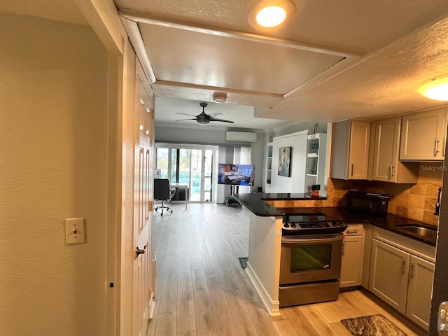 880 Mandalay Ave Unit C206, Clearwater, FL 33767 - kitchen with stainless steel electric stove, a wall mounted AC, dark countertops, a peninsula, and light wood-type flooring