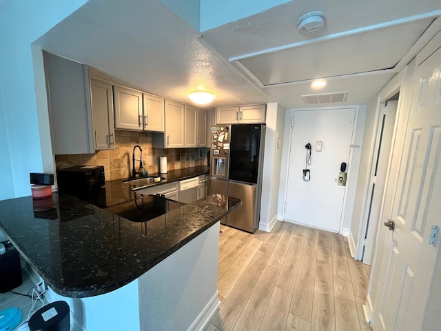 880 Mandalay Ave Unit C206, Clearwater, FL 33767 - kitchen featuring stainless steel fridge, dishwasher, a peninsula, light wood-type flooring, and dark stone counters