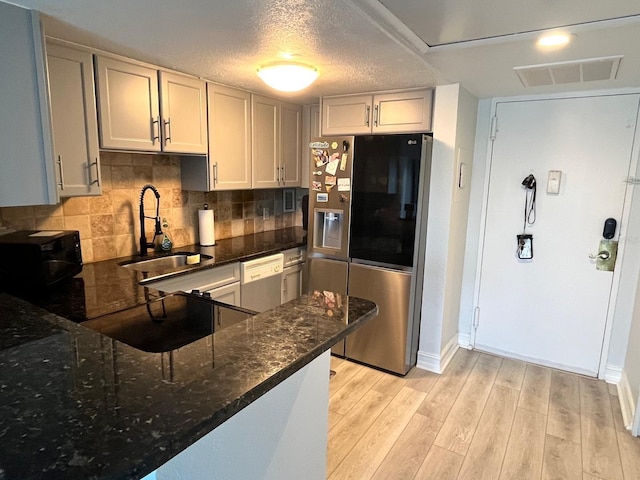 880 Mandalay Ave Unit C206, Clearwater, FL 33767 - kitchen featuring stainless steel fridge, black microwave, dishwasher, dark stone countertops, and light wood-style flooring