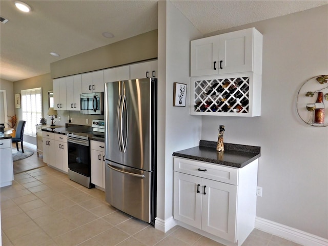 11802 Aintree Ct, Trinity, FL 34655 - kitchen with stainless steel appliances, white cabinetry, dark countertops, light tile patterned floors, and recessed lighting