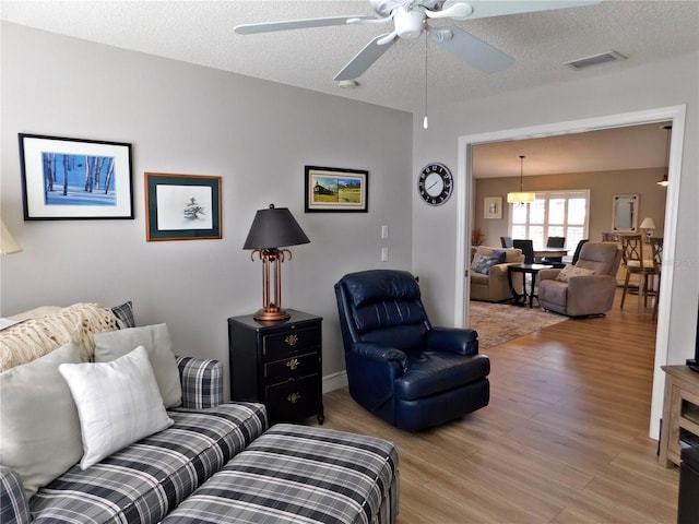 11802 Aintree Ct, Trinity, FL 34655 - living room with light wood-style floors, ceiling fan, and a textured ceiling