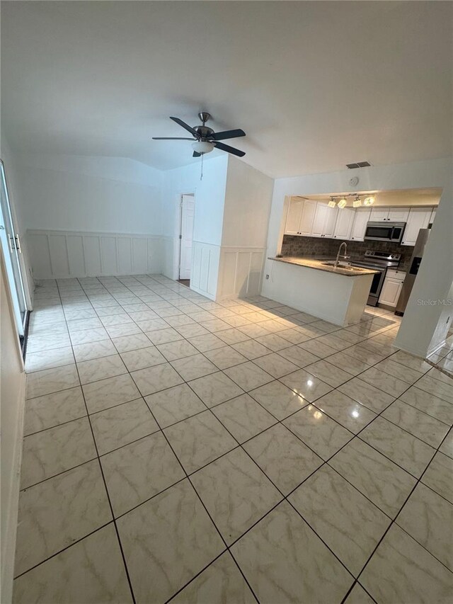 6133 Arthur Ave, New Port Richey, FL 34653 - unfurnished living room with wainscoting, a ceiling fan, and a decorative wall
