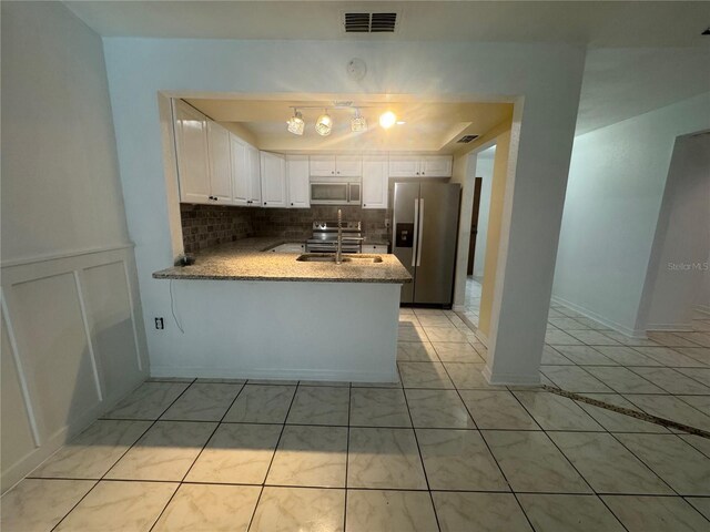 6133 Arthur Ave, New Port Richey, FL 34653 - kitchen with stainless steel appliances, a peninsula, white cabinets, and backsplash