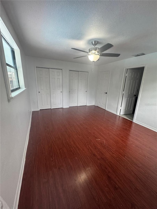 6133 Arthur Ave, New Port Richey, FL 34653 - unfurnished bedroom featuring wood finished floors, a textured ceiling, two closets, and a ceiling fan