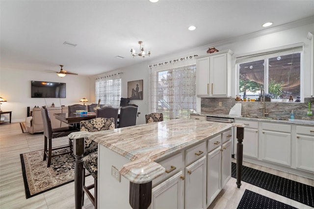 11132 Running Pine Dr, Riverview, FL 33569 - kitchen with decorative backsplash, a kitchen island, light tile patterned floors, light stone countertops, and recessed lighting