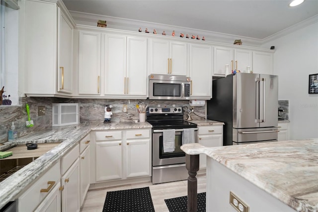 11132 Running Pine Dr, Riverview, FL 33569 - kitchen with appliances with stainless steel finishes, white cabinets, crown molding, tasteful backsplash, and light stone countertops