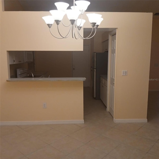 7674 37th Street Cir E, Sarasota, FL 34243 - kitchen with a chandelier, freestanding refrigerator, light tile patterned floors, light countertops, and a peninsula