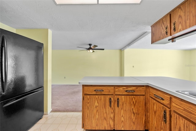 4371 Otter Way, New Port Richey, FL 34653 - kitchen featuring freestanding refrigerator, light countertops, a ceiling fan, brown cabinets, and a textured ceiling