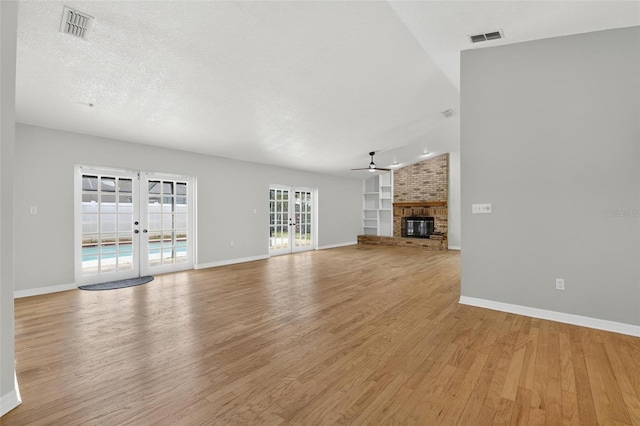 12331 Yellow Rose Cir, Riverview, FL 33569 - unfurnished living room with french doors, a ceiling fan, light wood finished floors, a fireplace, and built in features