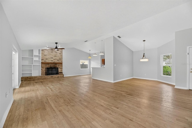 12331 Yellow Rose Cir, Riverview, FL 33569 - unfurnished living room with ceiling fan, vaulted ceiling, light wood finished floors, built in features, and a brick fireplace