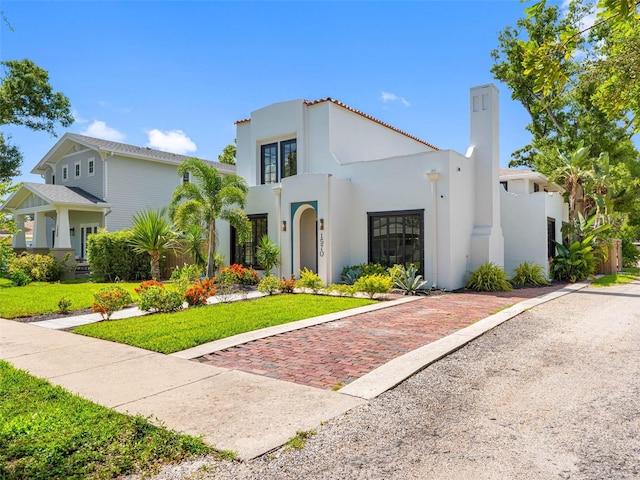 1570 48th Ave N, Saint Petersburg, FL 33703 - mediterranean / spanish-style home with stucco siding, a chimney, and a front lawn
