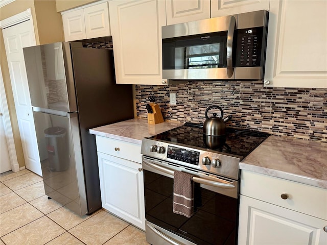 6801 34th Ave W, Bradenton, FL 34209 - kitchen featuring appliances with stainless steel finishes, tasteful backsplash, light tile patterned floors, and white cabinetry