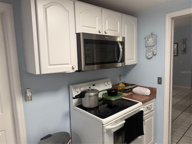 9705 Kingsburgh Ct, Tampa, FL 33615 - kitchen featuring white electric stove, stainless steel microwave, light tile patterned floors, and white cabinetry