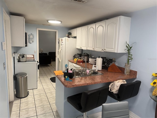 9705 Kingsburgh Ct, Tampa, FL 33615 - kitchen featuring stove, a peninsula, white cabinets, a kitchen breakfast bar, and freestanding refrigerator