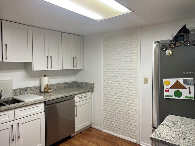 7518 Dolonita Dr Unit 7518, Tampa, FL 33615 - kitchen with appliances with stainless steel finishes, brick wall, wood finished floors, and white cabinetry