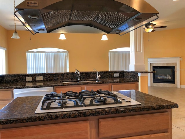 6517 Channelside Dr, New Port Richey, FL 34652 - kitchen featuring white gas stovetop, ventilation hood, light tile patterned flooring, dishwashing machine, and a tiled fireplace