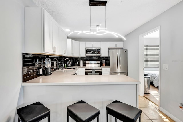 5682 25th Street Cir E, Bradenton, FL 34203 - kitchen featuring appliances with stainless steel finishes, tasteful backsplash, light countertops, a peninsula, and light tile patterned floors