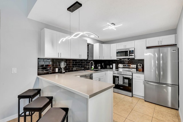 5682 25th Street Cir E, Bradenton, FL 34203 - kitchen with appliances with stainless steel finishes, a peninsula, backsplash, a breakfast bar area, and white cabinets