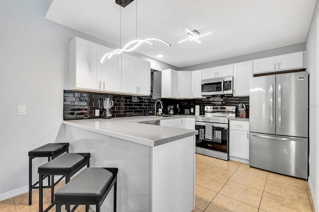 5682 25th Street Cir E, Bradenton, FL 34203 - kitchen with appliances with stainless steel finishes, a peninsula, a kitchen breakfast bar, white cabinetry, and tasteful backsplash