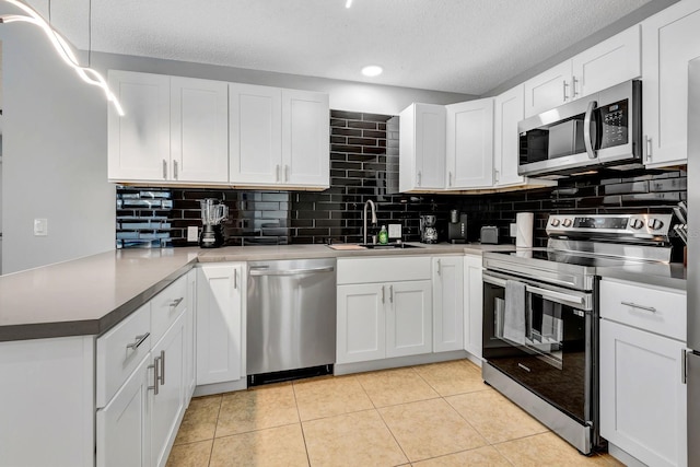 5682 25th Street Cir E, Bradenton, FL 34203 - kitchen featuring appliances with stainless steel finishes, a peninsula, a textured ceiling, tasteful backsplash, and white cabinets
